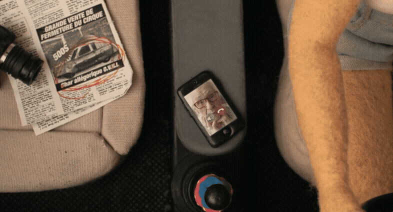 a gif from the short animated film "Madeleine" by Raquel Sancinetti, featuring an aerial view of a woman driving in a car, with a phone on the console and the real image of an elderly woman named Madeleine