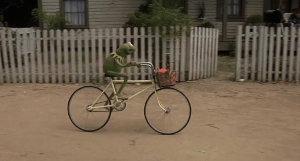 a gif of Kermit the Frog riding a bike