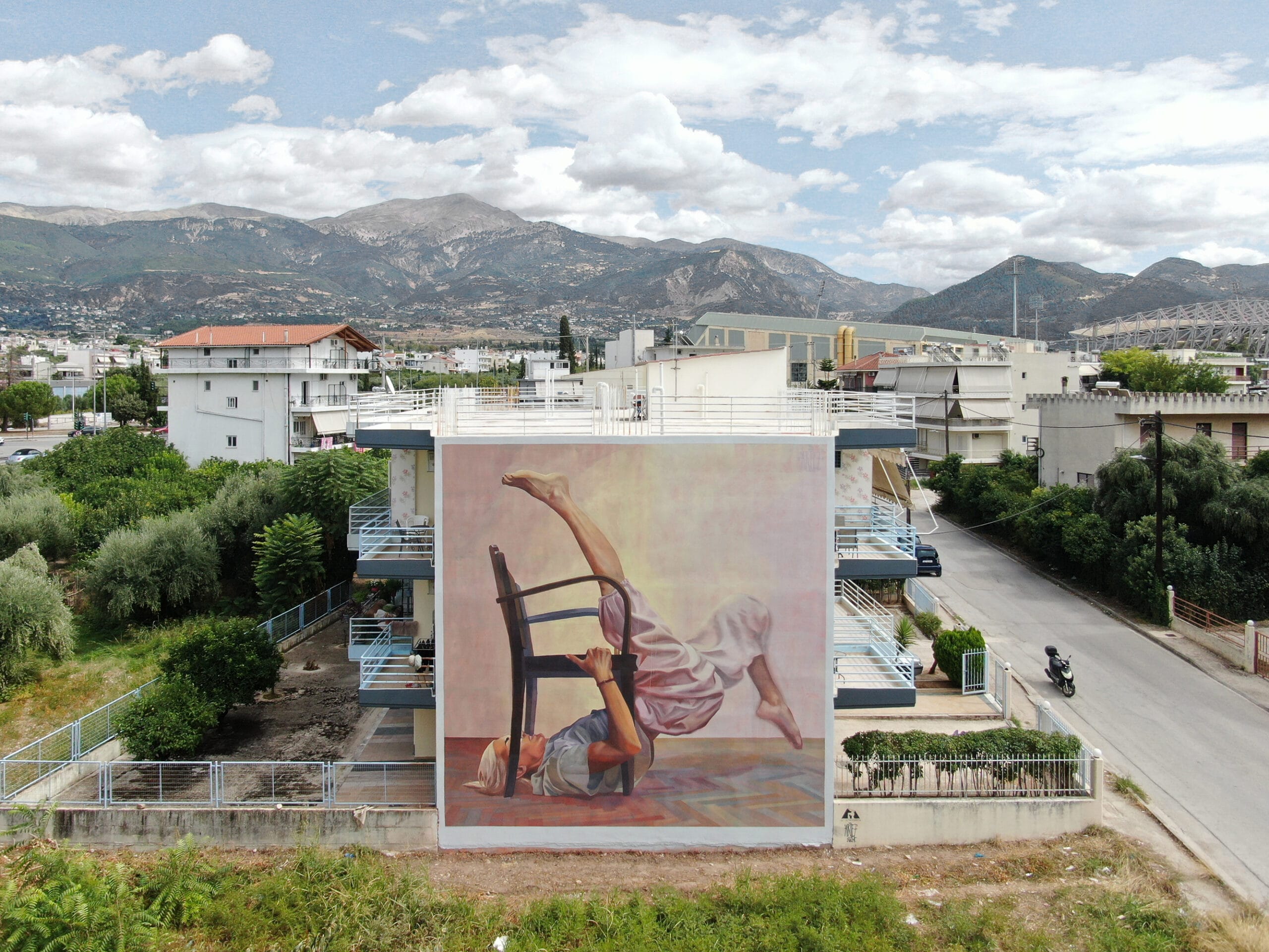 a mural on the side of a residential building of a dancer in an acrobatic pose with a chair