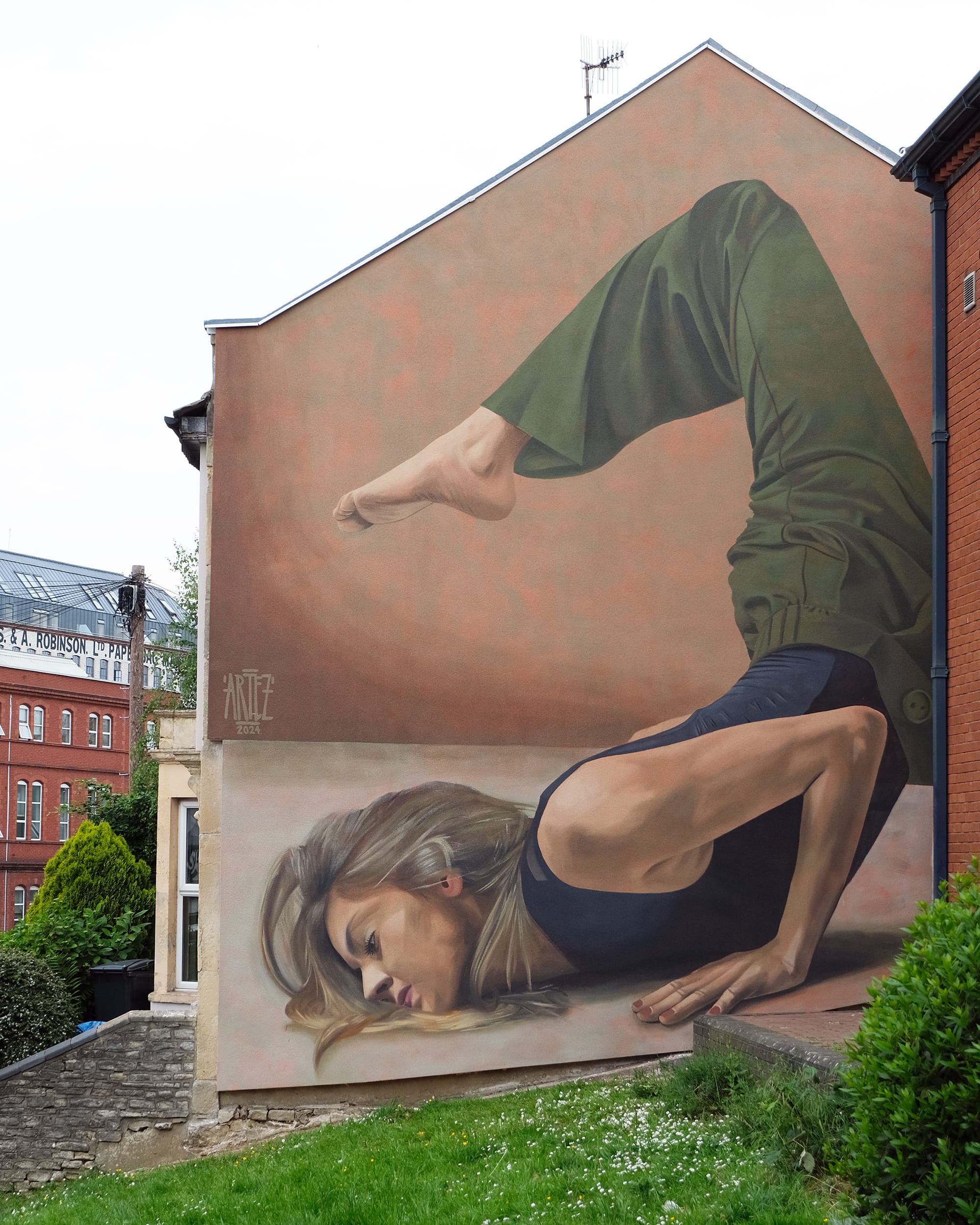 a mural on the side of a residential building of a dancer in an acrobatic pose
