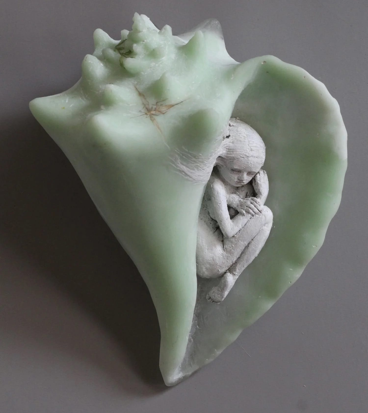 a small ceramic figure in a green shell