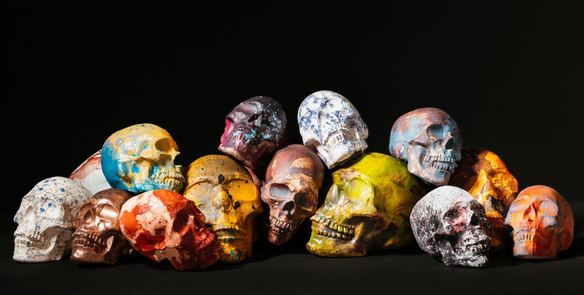 a cluster of human-like skulls with patterns and spray paint