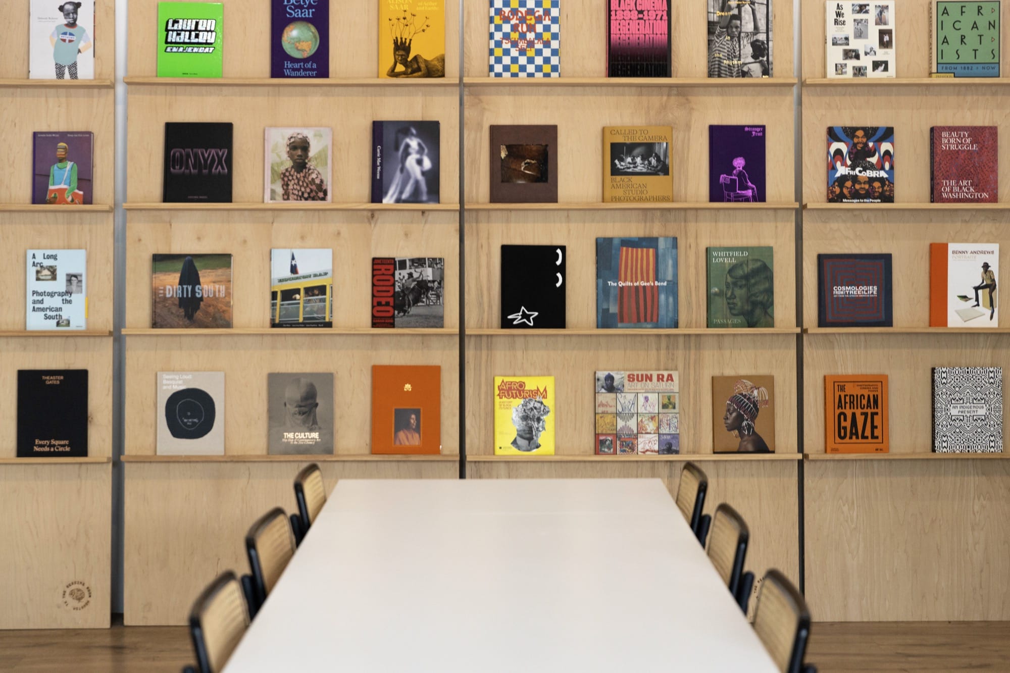 a bookshelf with art books facing out and a table in front