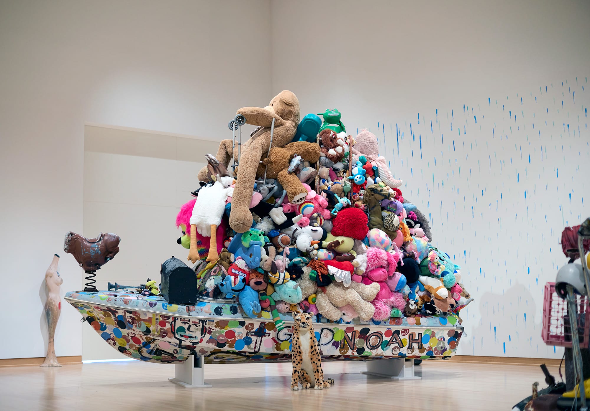 an installation of a bot topped with a tower of stuffed animals by Tyree Guyton against polka dotted walls