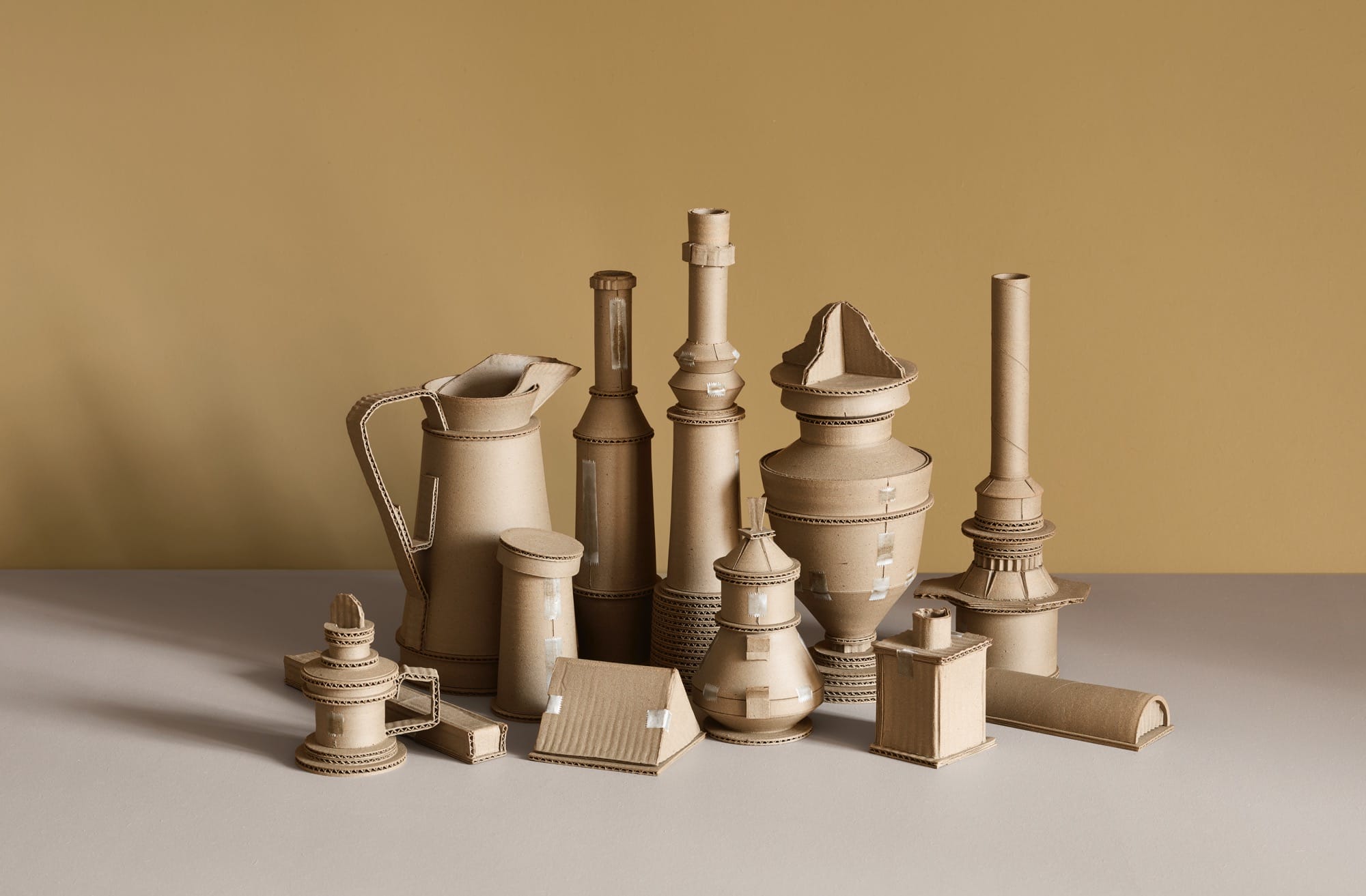 a series of ceramic vessels by Jacques Monneraud that resemble cardboard with tape, arranged to mimic a painting by Giorgio Morandi