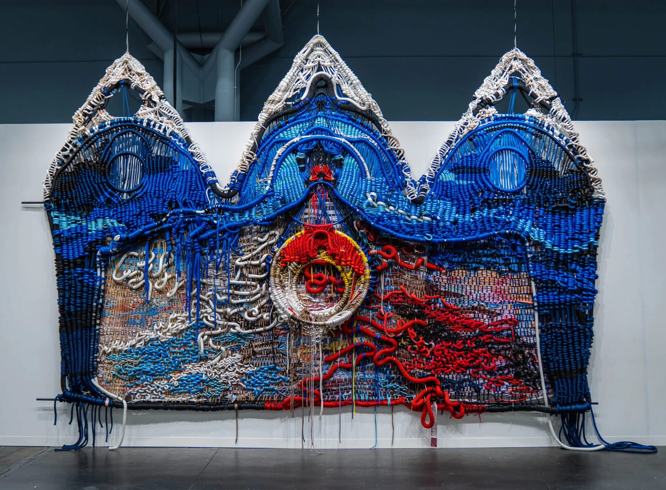 a colorfully knotted rope work by Jacqueline Surdell hanging from a bar